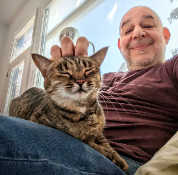 Cat sitter Mitch relaxing with a content cat sitting comfortably in his lap during an in-home visit in Midtown Toronto.